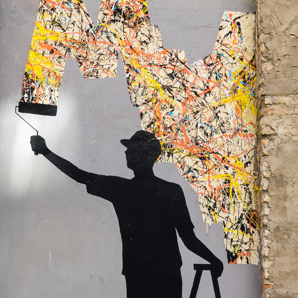 Street art of a man painting the wall