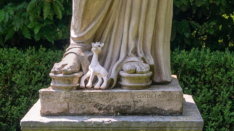 Small toy giraffe at feet of a caryatid