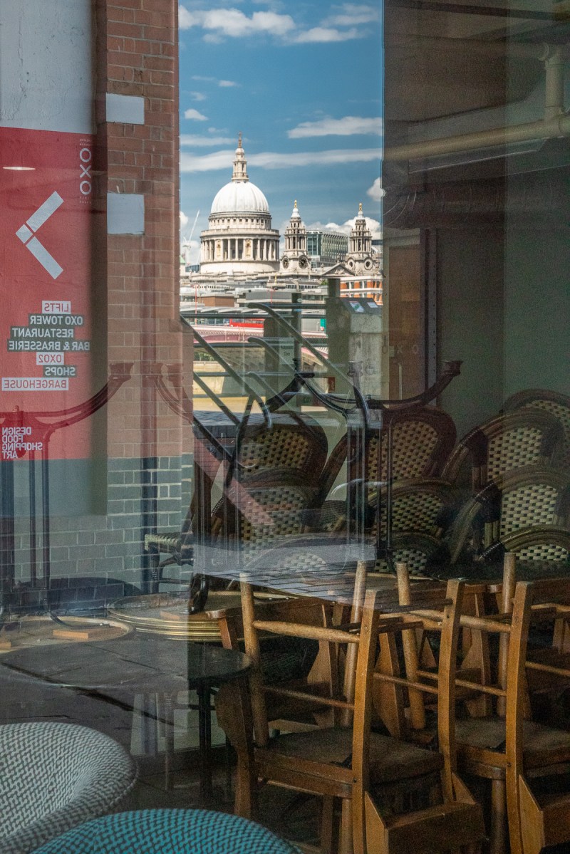 View of St Paul's Cathedral reflected in windows of an empty cafe