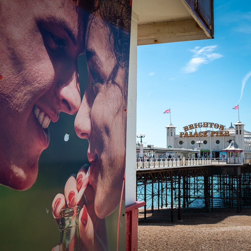 Side on view of a poster and Palace Pier beyond