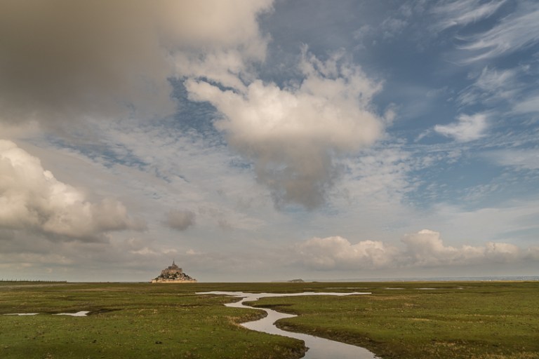 View to Mont St Michel on horizon and cloudy sky above