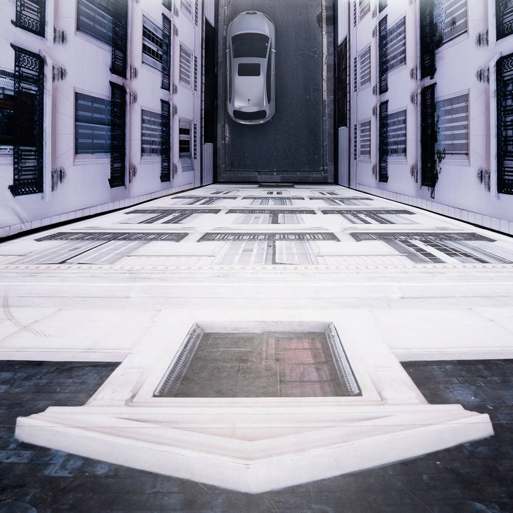 Street art looking down the side of a tall building to a car parked below