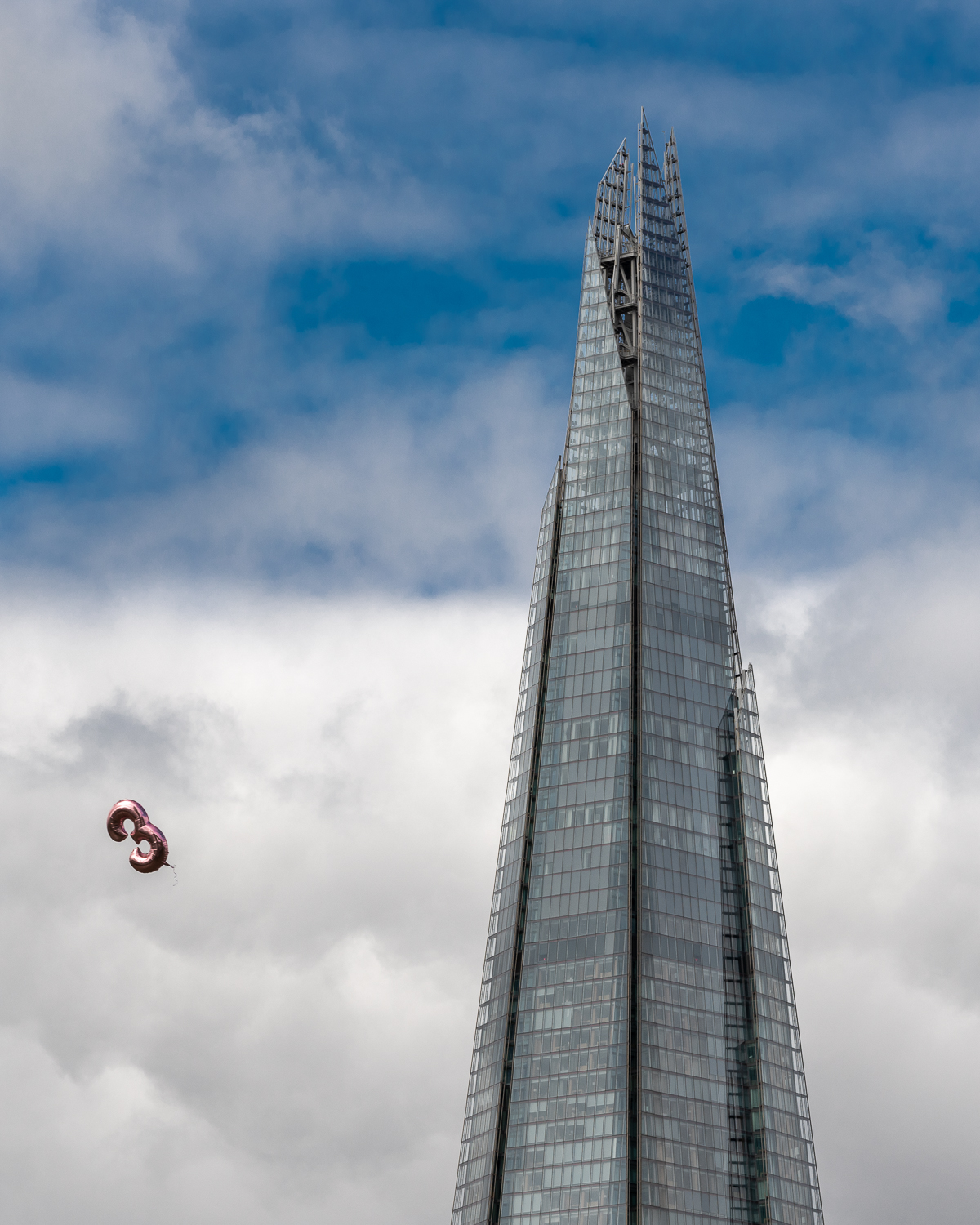 A pink balloon in shape of a 3 flying past The Shard